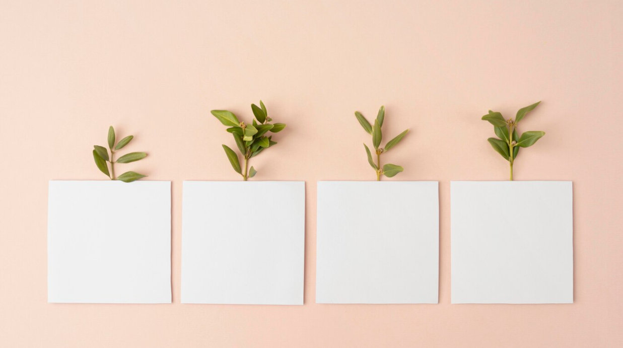 plants behind the white paper squares on a pink background