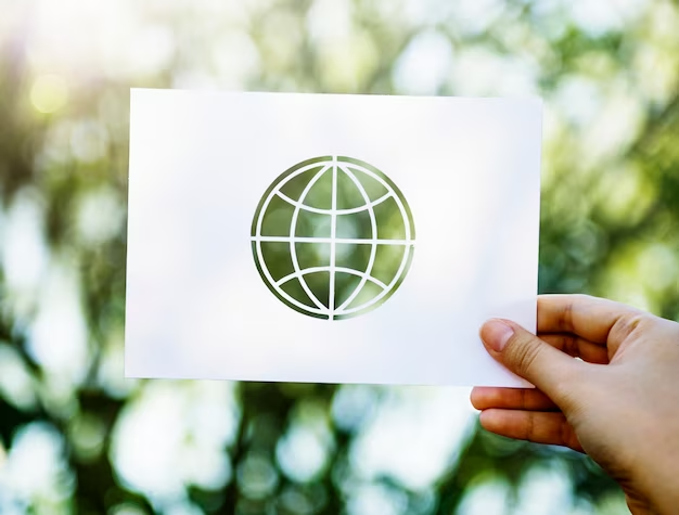 Hand holding a cutout of Earth against a backdrop of green plants